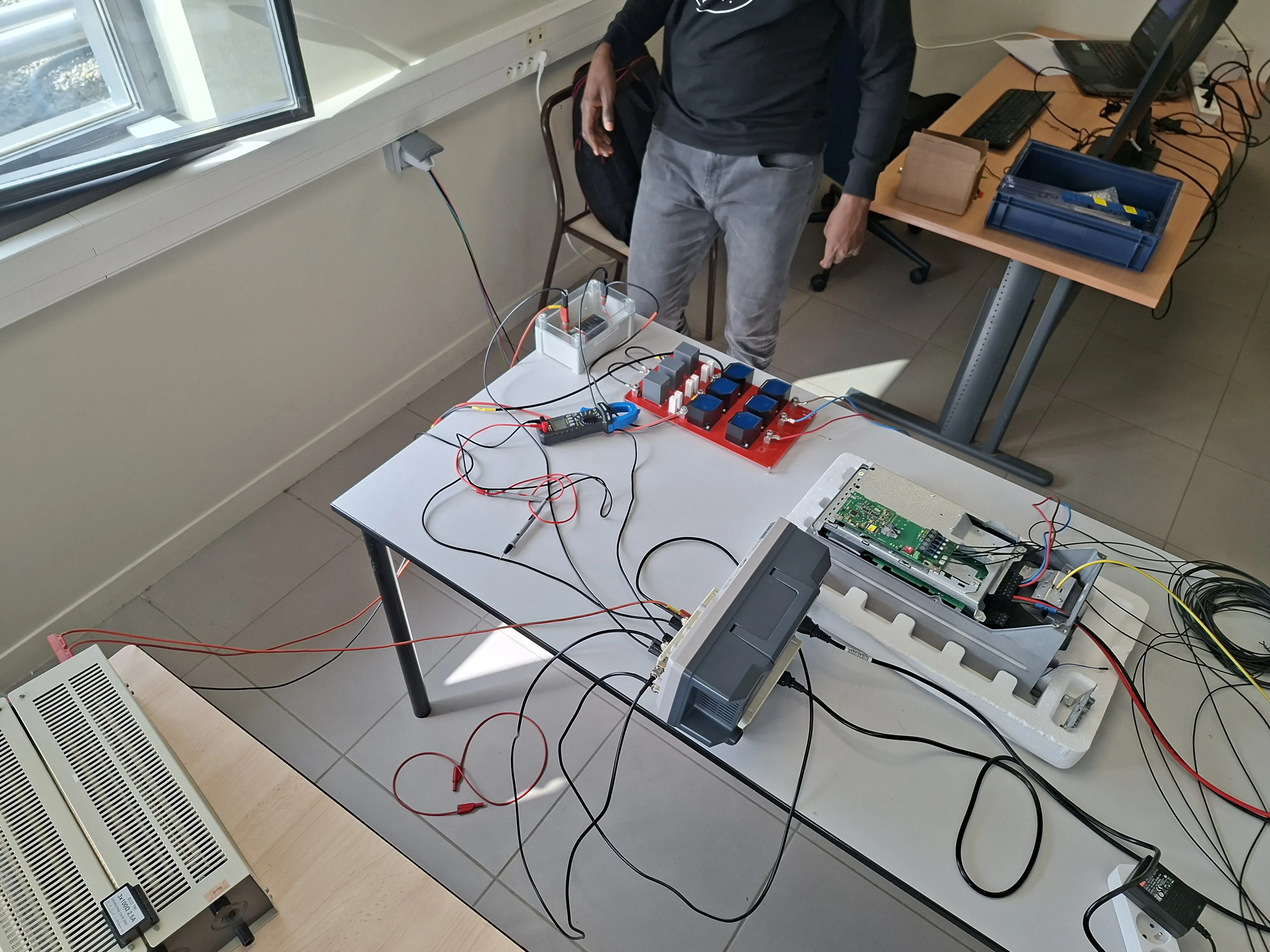 Opened Danfoss converter on the bench with a red LC-filter prototype and a DC supply